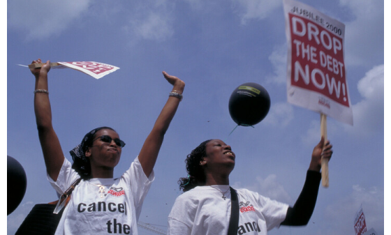 Protestors holding placards reading "Drop the debt now!"