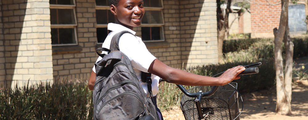 Ester Simon standing with her bicycle in her school uniform