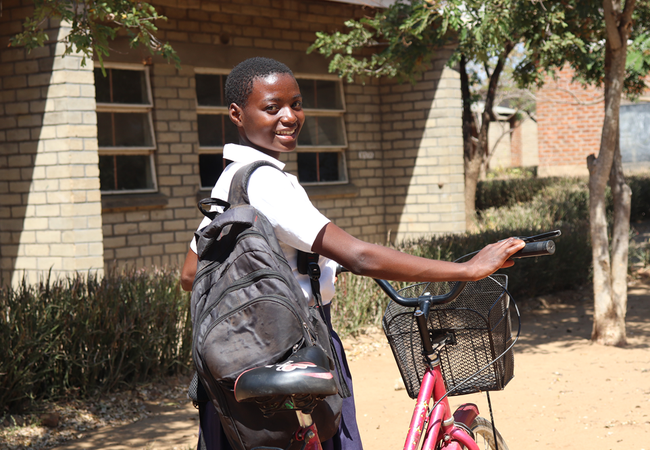 Ester Simon standing with her bicycle in her school uniform