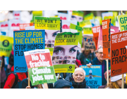 A procession of campaigns holding placards reading "We won't look away" and "Rise up for the climate"