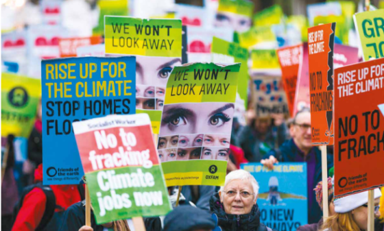 A procession of campaigns holding placards reading "We won't look away" and "Rise up for the climate"