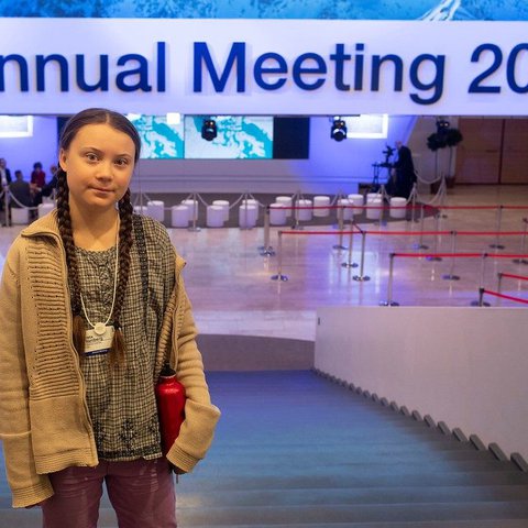 A picture of Greta Thunberg wearing her trademark plaits in a conference centre.