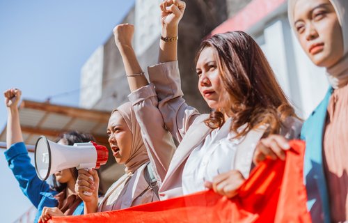 A group of activists raise their fists and colourful banners during a protest