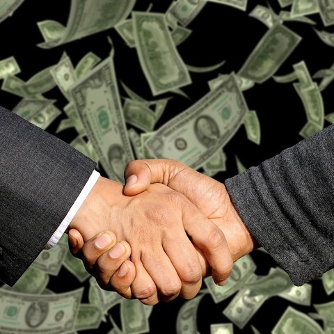 Two male hands in a handshake pose with a background of dollar bills floating down.