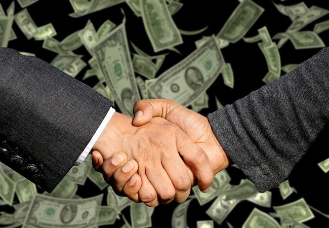 Two male hands in a handshake pose with a background of dollar bills floating down.