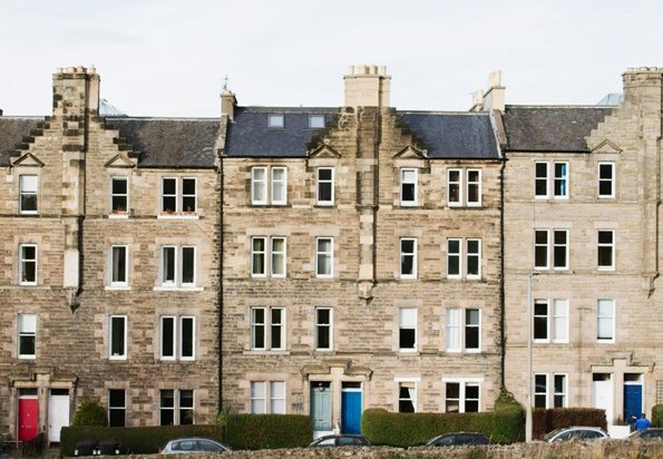 Image of a row of houses with green grass in the foreground and blue sky