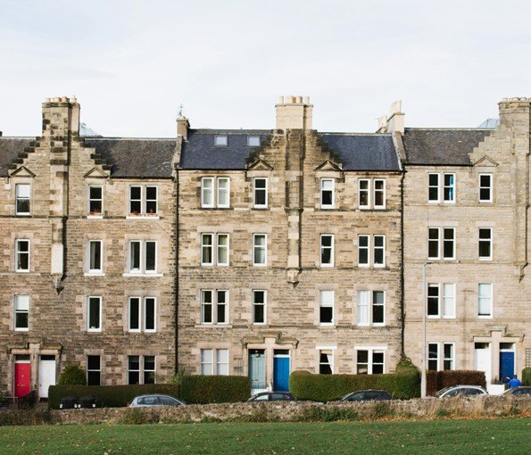 Image of a row of houses with green grass in the foreground and blue sky