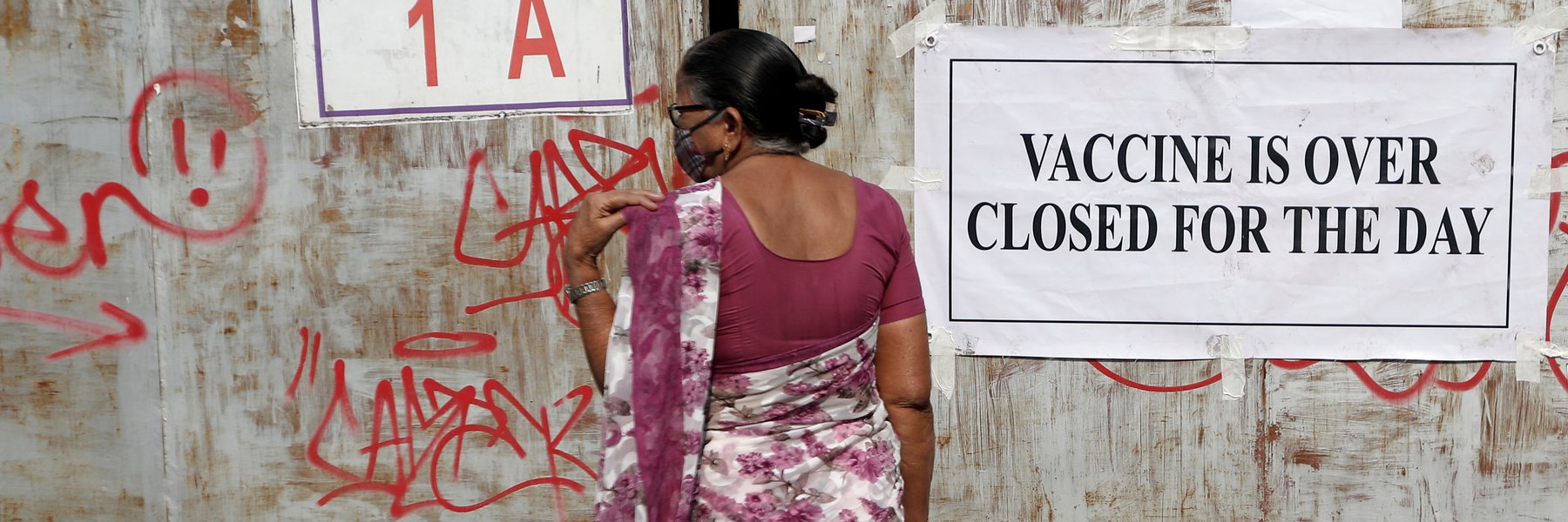 A woman stands in front of a closed gate of a vaccination centre which was closed due to unavailability of the supply of COVID-19 vaccine, in Mumbai, India. Photo: REUTERS/Francis M