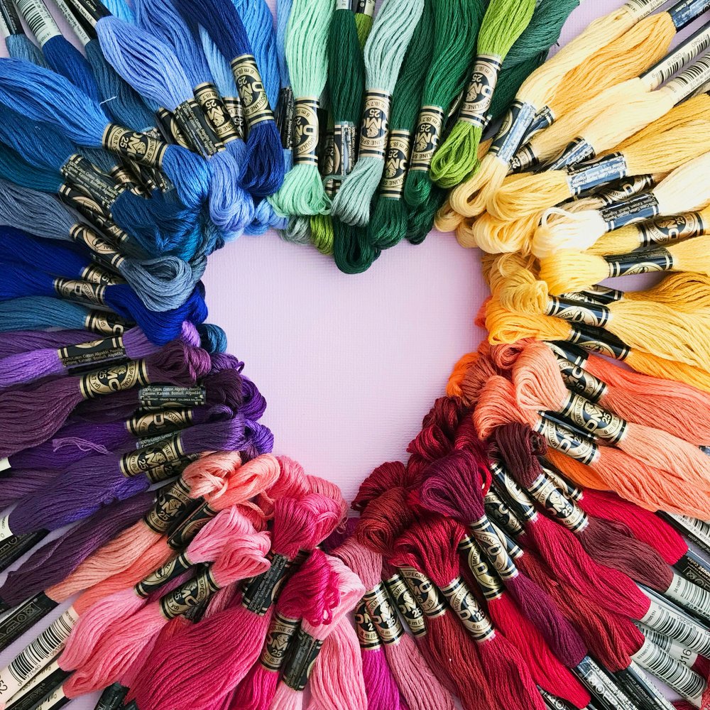 Multi-coloured sewing threads placed together to make the shape of a heart