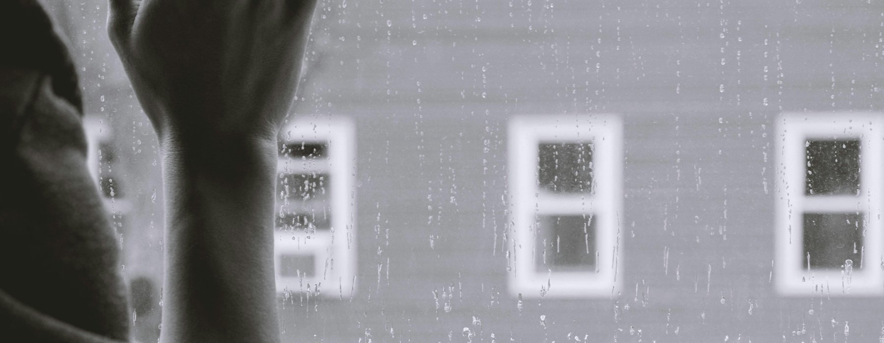Hand on a rain covered window