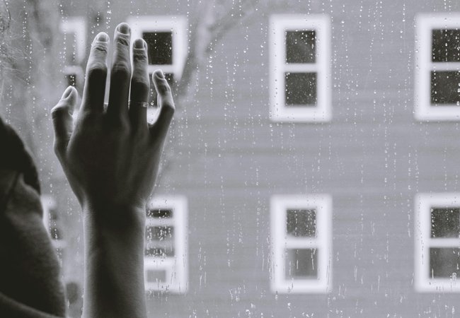 Hand on a rain covered window