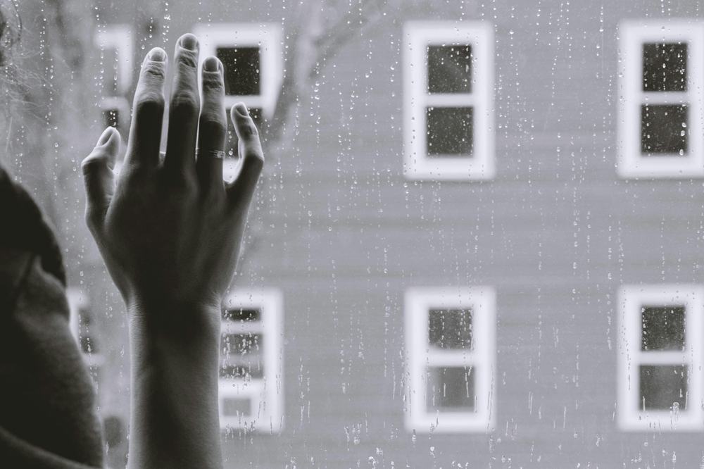 Hand on a rain covered window