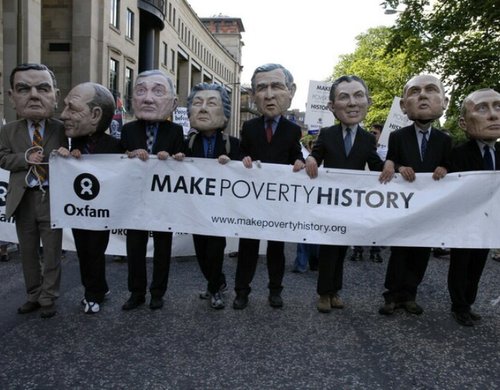 Campaigners wearing comically big masks of world leaders hold a banner reading 'Make Poverty History'