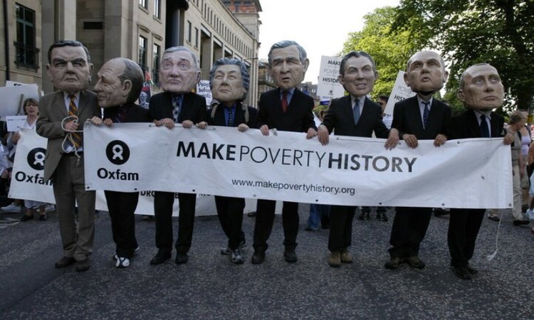 Campaigners wearing comically big masks of world leaders hold a banner reading 'Make Poverty History'