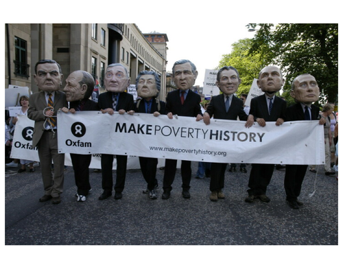 Campaigners wearing comically big masks of world leaders hold a banner reading 'Make Poverty History'