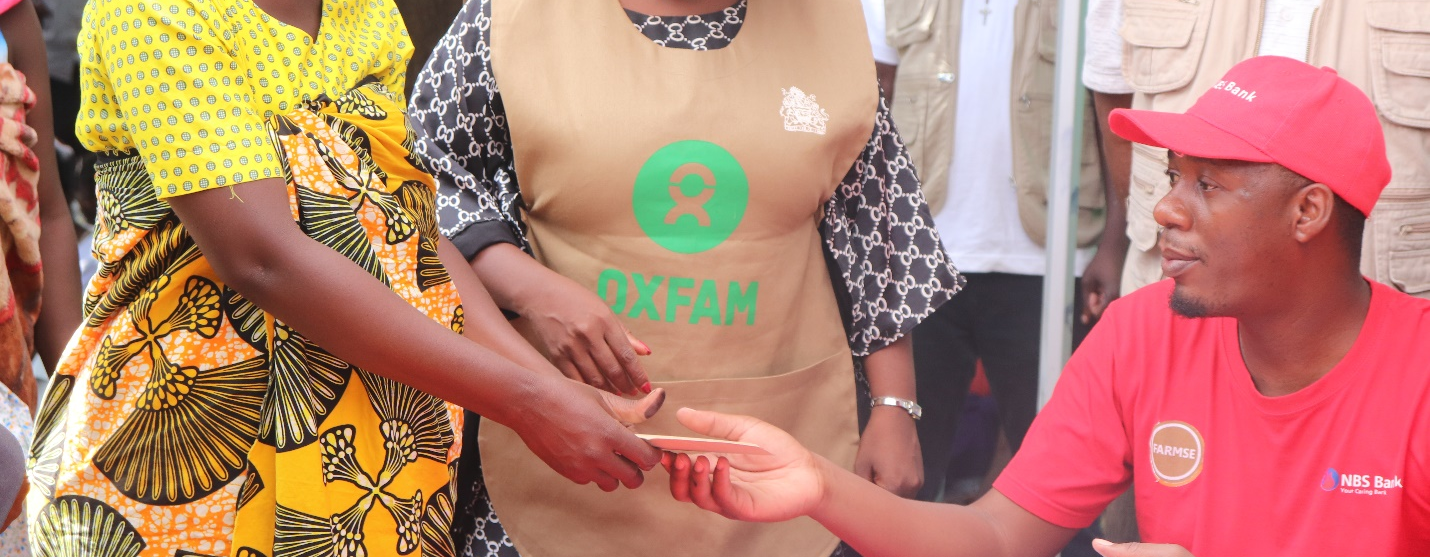 Maria receives her cash transfer from a member of staff sitting at a desk