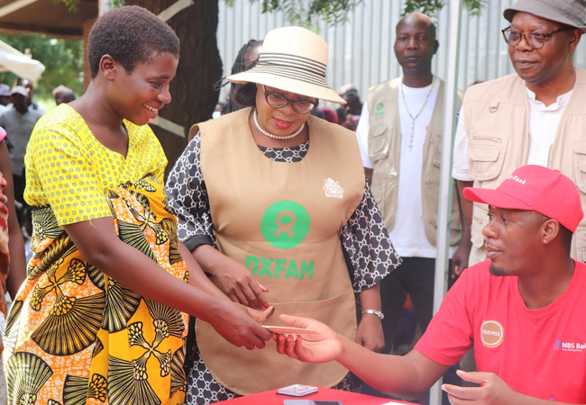 Maria receives her cash transfer from a member of staff sitting at a desk