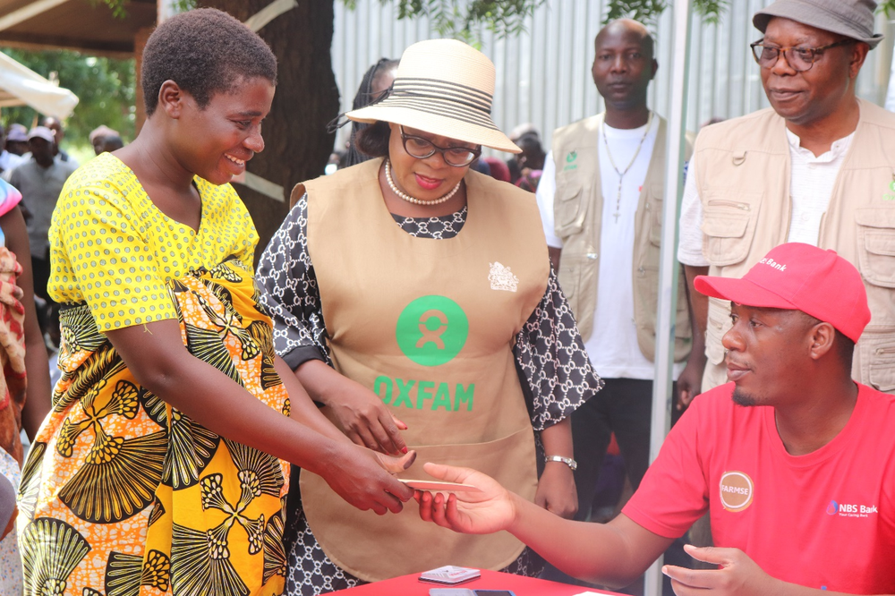 Maria receives her cash transfer from a member of staff sitting at a desk