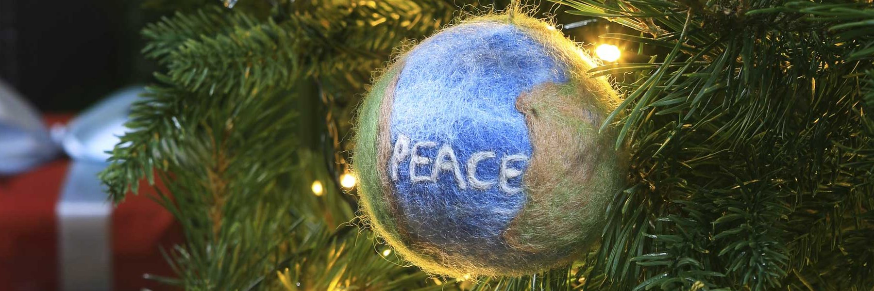 A felt Peace bauble hangs in a Christmas tree