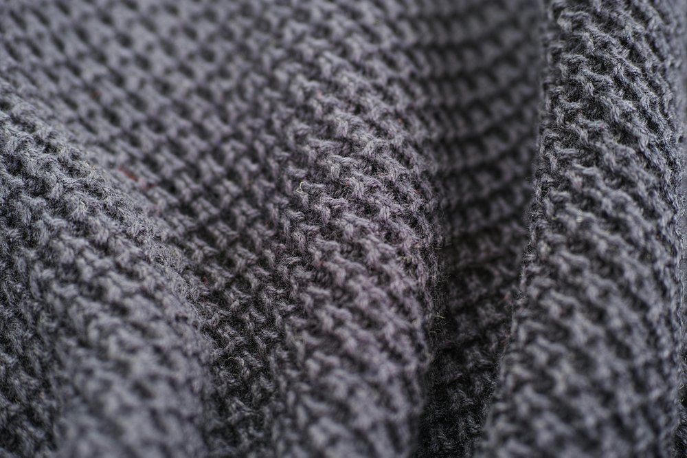 A zoomed in picture of a dark grey knitted jumper.