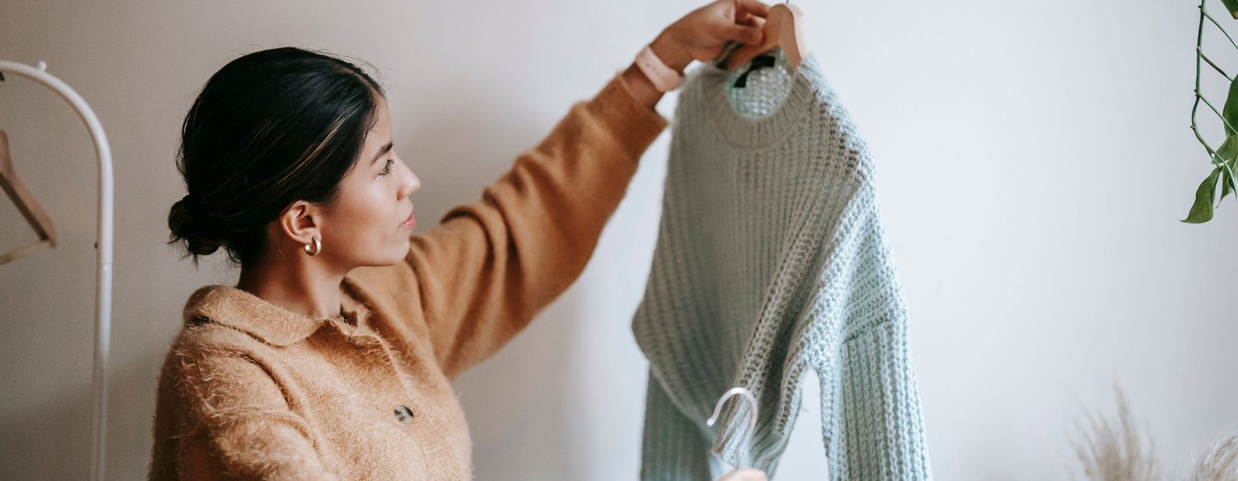 A person deciding between two pieces of clothing in an indoor space