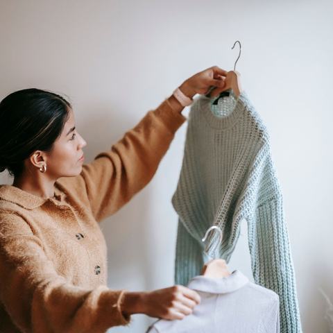 A person deciding between two pieces of clothing in an indoor space