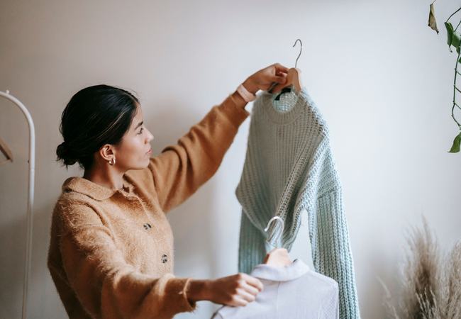 A person deciding between two pieces of clothing in an indoor space