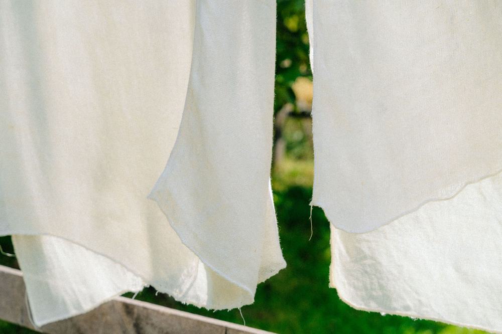 Cream linen fabric hanging on a washing line with grass peaking through.