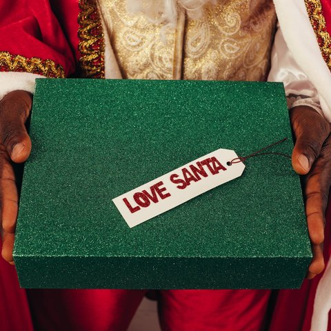 Santas hands passing a glittery green box that says Love Santa