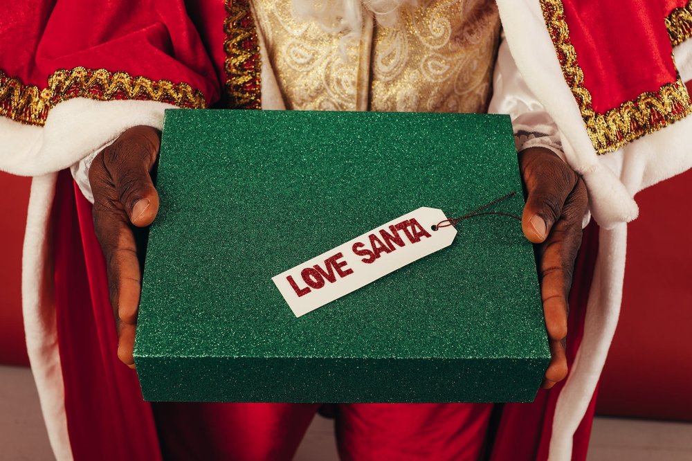 Santas hands passing a glittery green box that says Love Santa