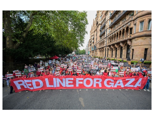 A bloc of campaigners in a march holding a 'Red Line for Gaza' banner