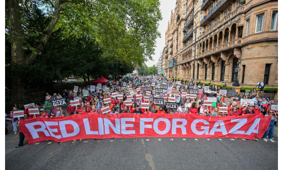 A bloc of campaigners in a march holding a 'Red Line for Gaza' banner