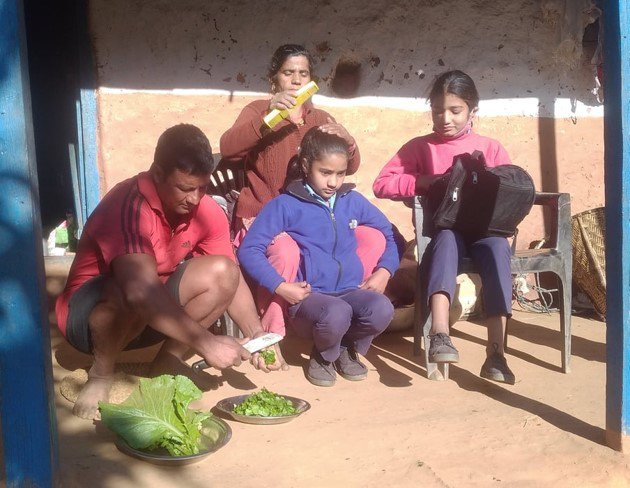 A father in Nepal prepares some vegetables while a mother combs her daughter's hair