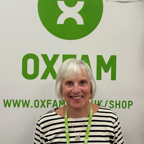 Photo of Sandra smiling in front of an Oxfam sign