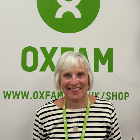 Photo of Sandra smiling in front of an Oxfam sign