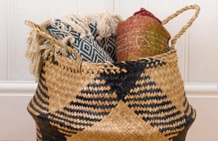 A seagrass basket filled with rolled blankets and rugs