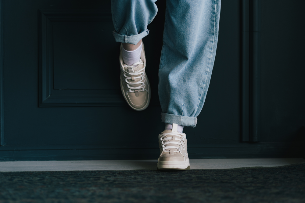 A pair of baggy jeans that come in at the ankles on a model but only the legs and shoes can be seen.