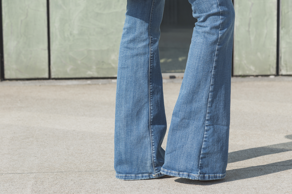 An image of the bottom of a pair of pale blue flared jeans on a person.