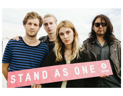 Wolf Alice band holding a sign reading "Stand as One"