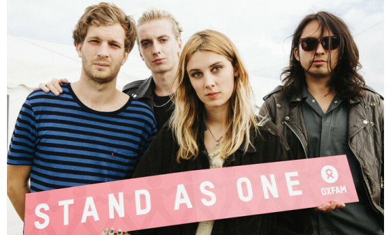 Wolf Alice band holding a sign reading "Stand as One"