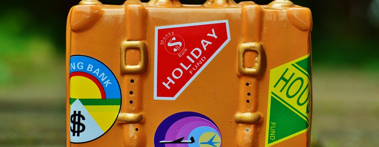 An orange suitcase covered with colourful holiday-themed stickers.