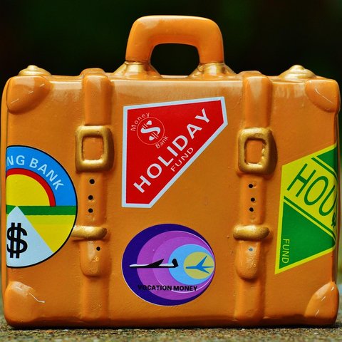 An orange suitcase covered with colourful holiday-themed stickers.
