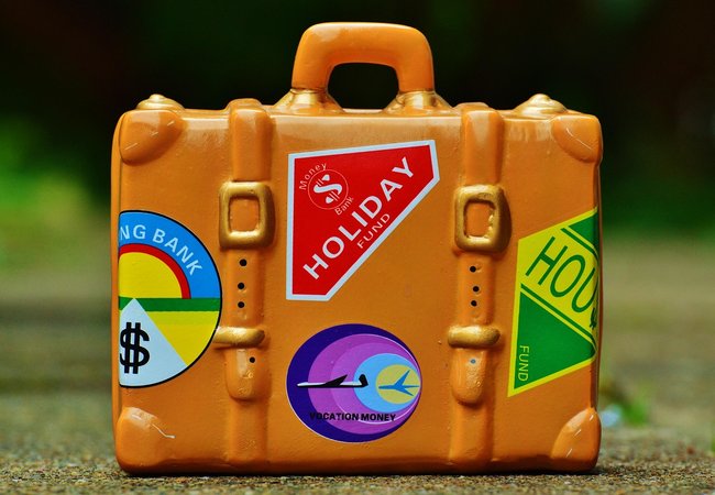 An orange suitcase covered with colourful holiday-themed stickers.