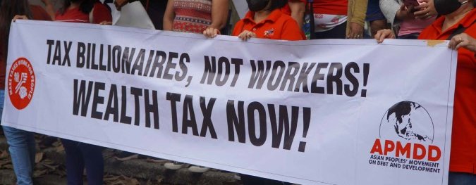 A group of women at a demonstration holding a large banner that reads "Tax billionaires, not workers! Wealth tax now!" The foreground sponsor logo is for the Asian Peoples' Movement on Debt and Development.