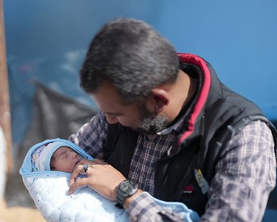 Fedaa holds his newly born baby boy in his tent in Tal Sultan in Rafah