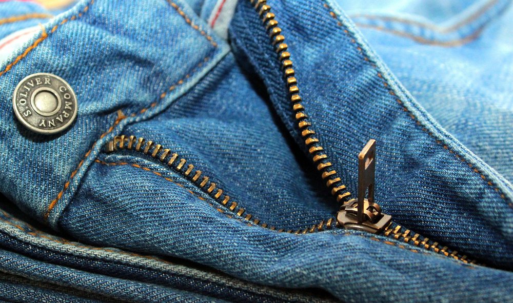 A close up of the zip on a pair of blue jeans